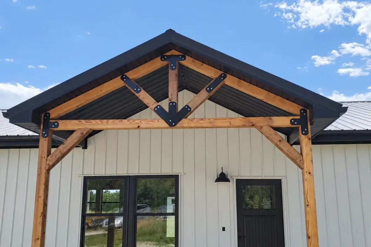 Close-up of an exposed timber-frame gable entry with black steel connectors on a custom home