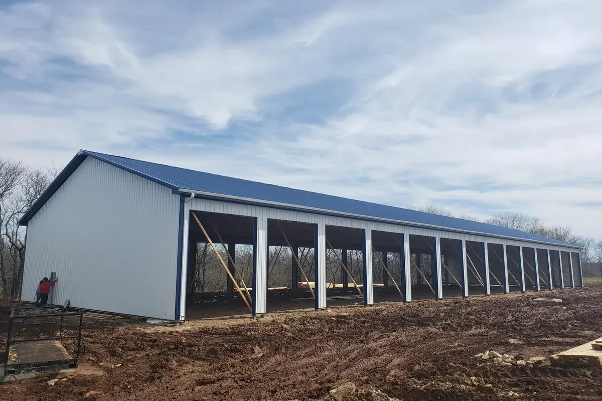 Large open-bay pole barn under construction, showing the post-frame structure