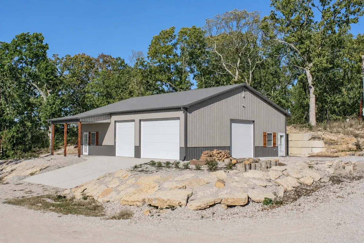 Gray three-bay garage with a covered entry and landscaped stone accents